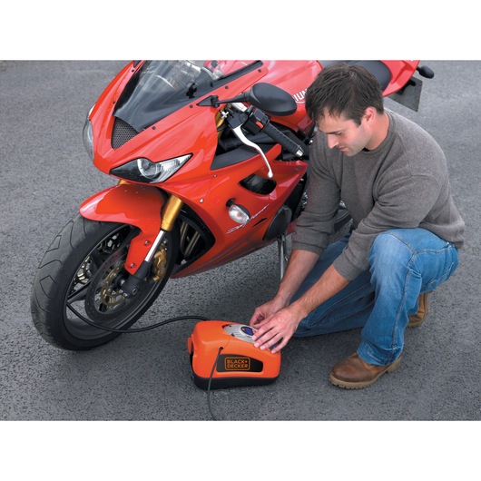 BLACKDECKER ASI300 portable air compressor inflating motorcycle tire outdoors, product in use.