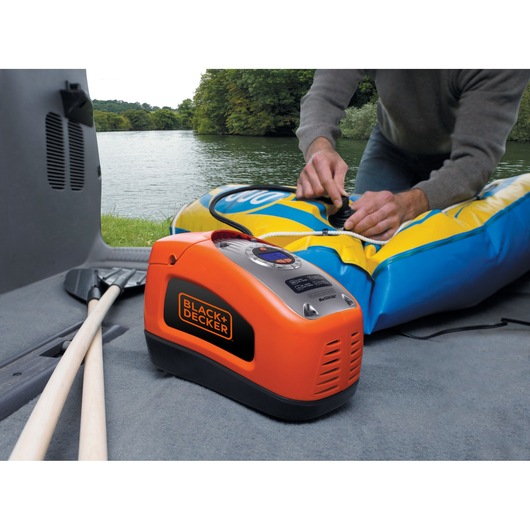 BLACKDECKER ASI300 portable orange air compressor inflating a blue and yellow raft near a lake.