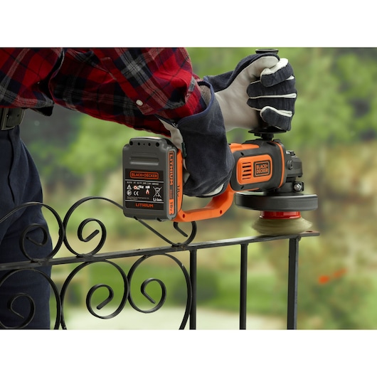 BLACKDECKER cordless angle grinder BCG720N in use on metal railing, orange and black design.