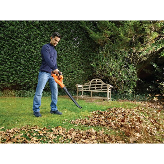 BLACKDECKER GWC1820PC leaf blower in use outdoors moving leaves on grass near bench.