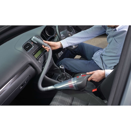 BLACKDECKER NV1210AV handheld vacuum cleaner used to clean car interior with flexible hose.